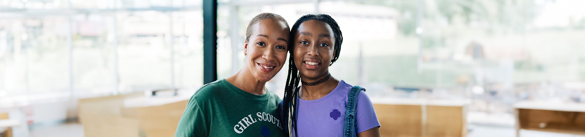  adult woman girl scout volunteer wearing vest outdoors with junior girl scout hiking 