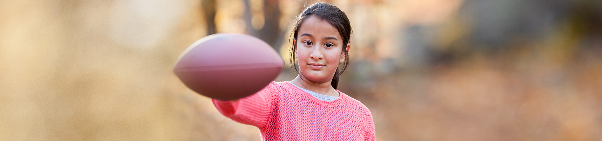  girl holding football looking at camera 